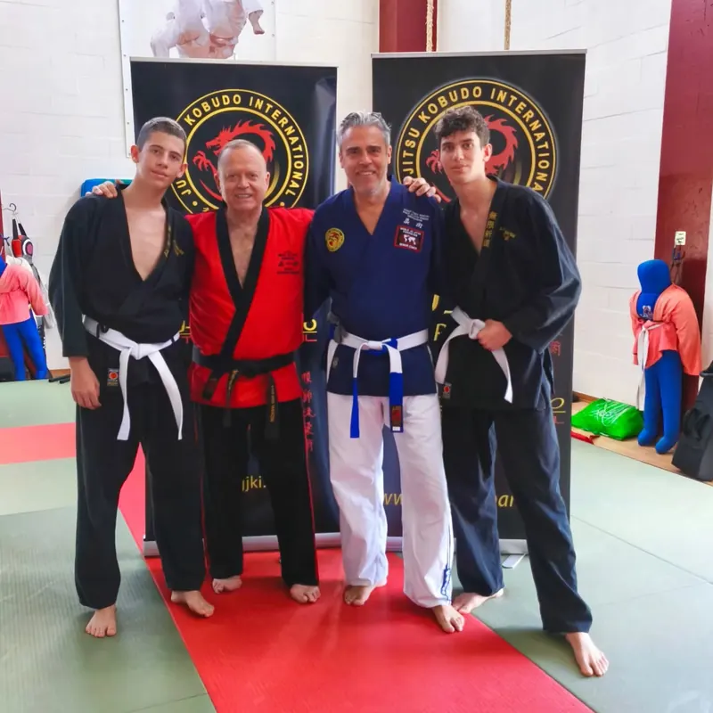 Foto di gruppo a uno stage, davanti agli stendardi della Ju Jitsu Kobudo International
