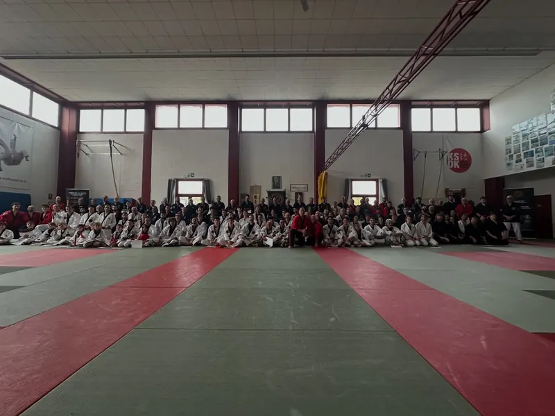 Stage in una grande palestra: decine di allievi seduti in fila sul tatami